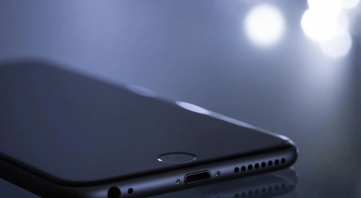 Close-up of a dark smartphone resting under soft blue light